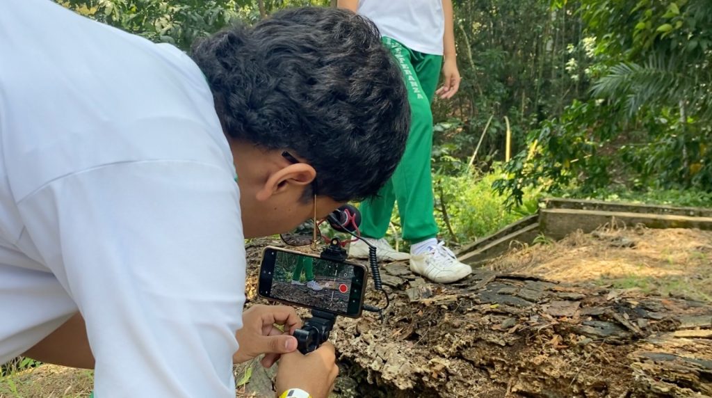 Un joven estudiante graba a otro mediante su celular y un soporte de mano, como parte del concurso de Smartfilm en el marco de la COP16.